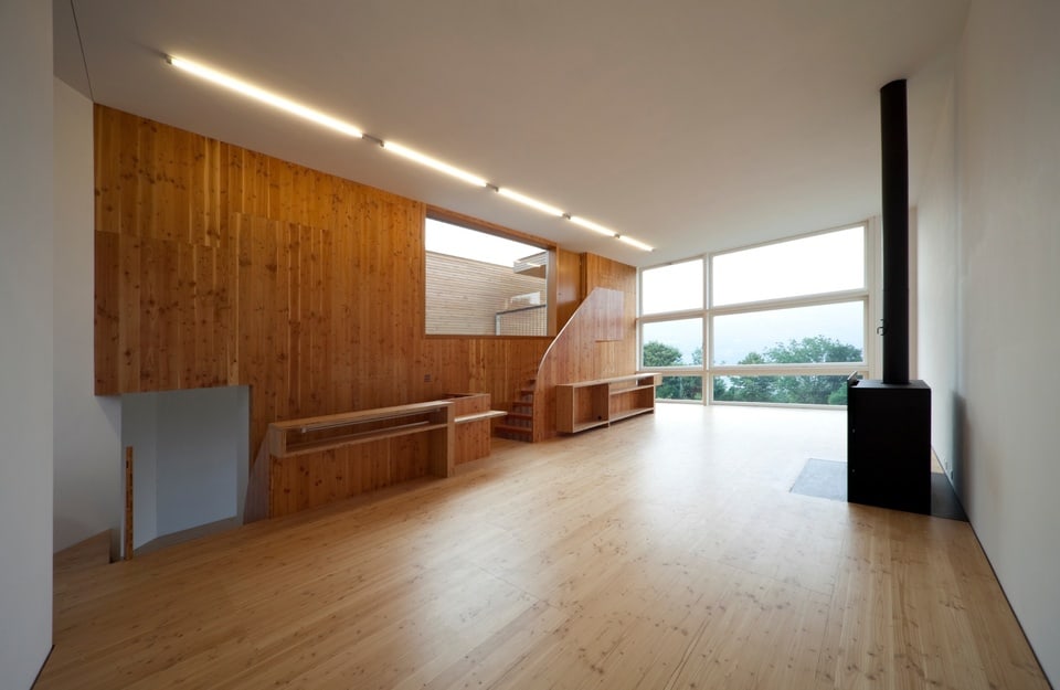 Interno contemporaneo con pareti e pavimento in legno e stufa nera